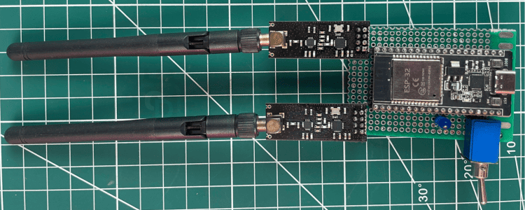 Fully assembled ESP32 Bluetooth jammer on perfboard showing two NRF24L01 PA+LNA modules, LiPo battery, toggle switch, and status LED