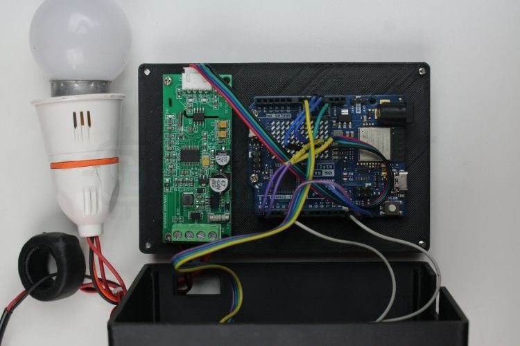 Assembled IoT-based smart grid monitoring hardware showing Arduino UNO R4 WiFi, PZEM-004T energy meter, and OLED display with all wiring connected